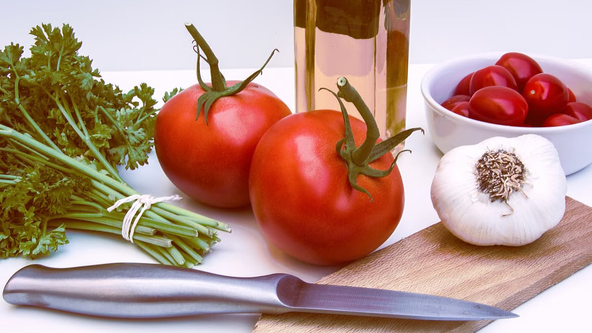 Fresh ingredients for healthy cooking featuring tomatoes, garlic, and herbs on a cutting board.